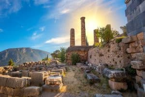 Ancient Delphi temple ruins with standing columns in brilliant sunlight, illuminating the sacred way to divine connection through Apollo's Oracle
