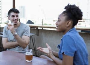 Two people having casual, intimate conversation at outdoor table, representing the two-way dialogue between devotee and deity