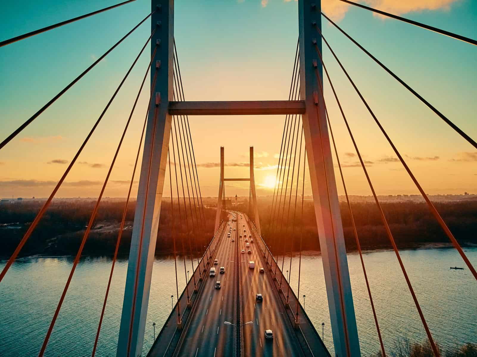Beautiful panoramic aerial drone view to cable-stayed Siekierkowski Bridge over the Vistula river and Warsaw City skyscrapers, Poland in gold red autumn colors in November evening at sunset