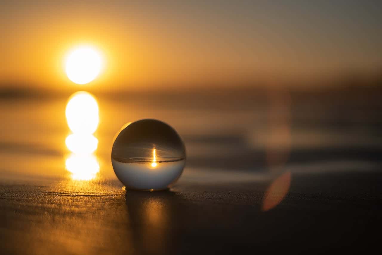 Crystal sphere reflecting Apollo's golden sunrise light in multiple glowing orbs on wooden surface, symbolizing sacred divination tools capturing and refracting divine illumination