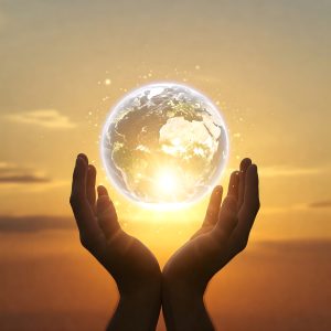 Hands holding a glowing translucent globe of Earth against golden sunset sky with sparkles of light, symbolizing the weight and honor of accepting the responsibility of being an oracle