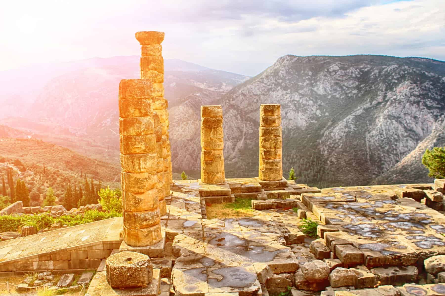 Temple of Apollo God of Truth at Delphi bathed in golden light, showing sacred ruins and columns with dramatic mountains
